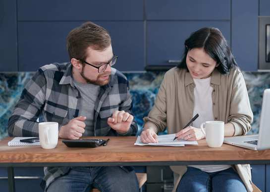 Photo d'un couple qui calcule leur assurance emprunt immobilier concernant la souscription d'un prêt immobilier.