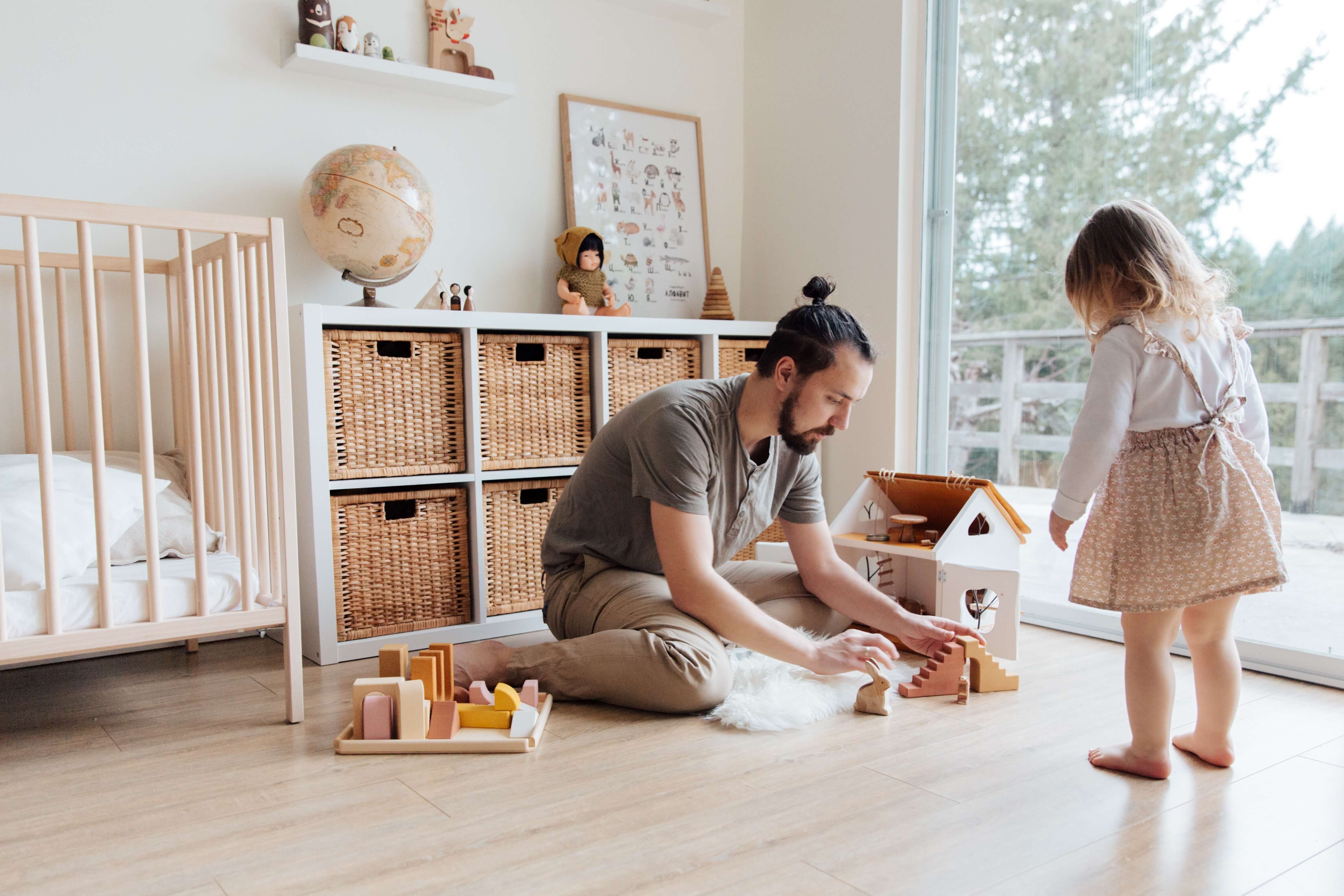 Photo d'un père qui joue avec sa fille. Il construit une maison avec de s jouets