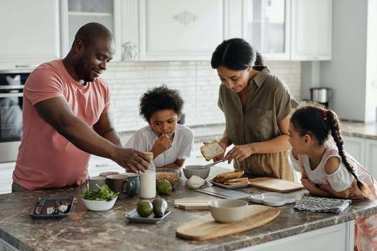Photo d'une famille dans leur cuisine. Les aprents ont souscrit un contrat d'assurance-vie, et ont désigné leurs enfants comme bénéficiaires du contrat d'assurance vie.