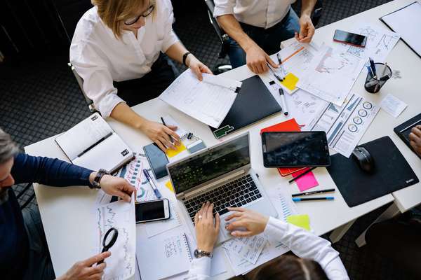 Photo de salariés autour de la table. Le chef d'entreprise a souscrit une assurance frais professionnels, permettant de couvrir les dépenses de personnels en cas d'arrêt de travail du dirigeant.