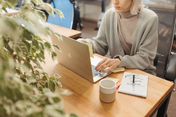 Photo d'une femme qui recherche sur son pc portable, un contrat prévoyance TNS avec l'option rente d'invalidité.