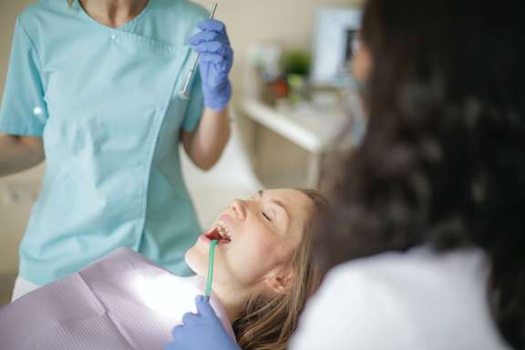 Photo d'un patiente chez sond entiste. Il lui pose un implant dentaire, une racine artificielle dans l'os de la mâchoire.