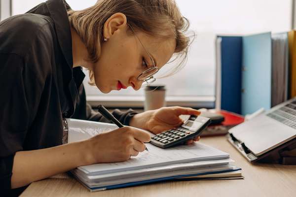 Photo d'une assurée, qui calcule les éléments de son contrat prévoyance tns forfaitaire.