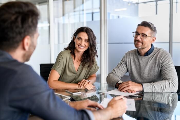 Photo d'un coupe dans le bureau de leur courtier en assurance prévoyance. Ces clients veulent souscrire une rente d'invalidité au barème professionnel, et non au barème croisé.