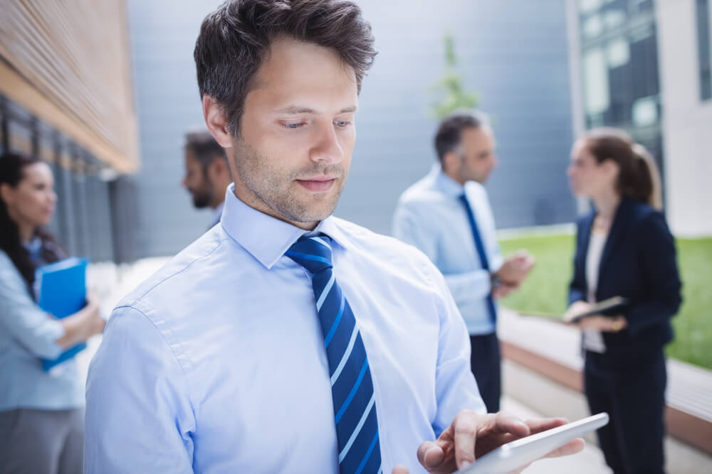 Un expert d'Avenir Courtage Solutions auditant les besoins d'un client sur une tablette pour une garantie frais professionnels.