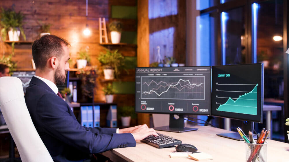 Un courtier en ligne devant son PC qui prépare une proposition d'investissement sur les ETF des contrats d'assurance-vie de ses clients.