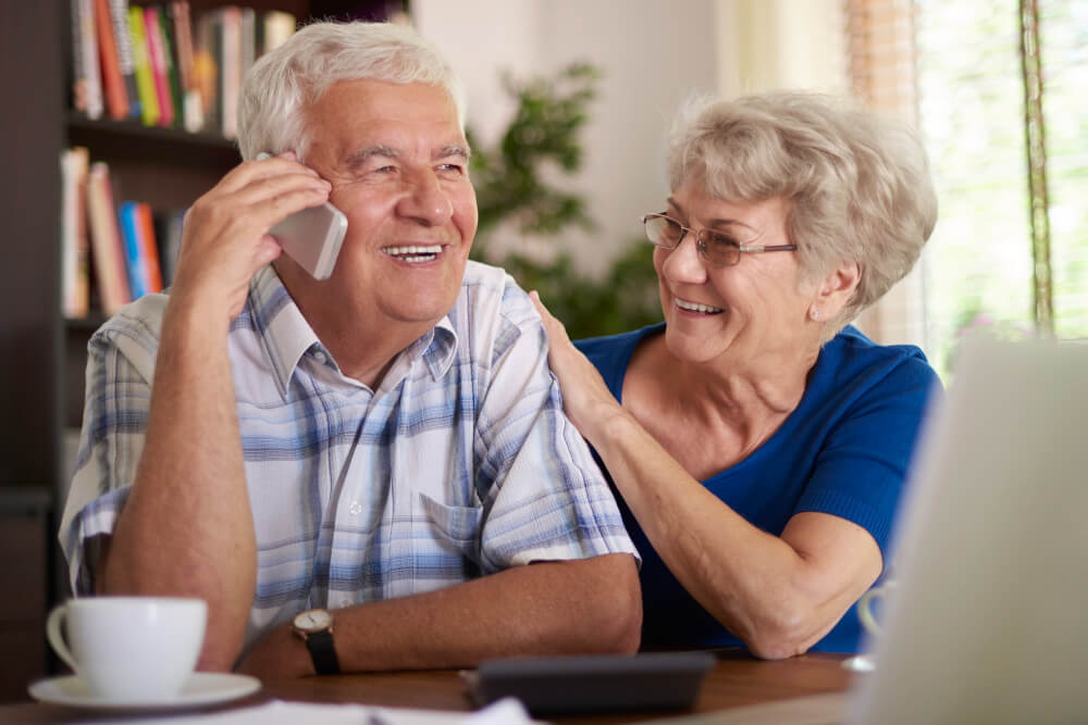 Un couple au téléphone avec leur courtier qui décide de verser sur son assurance-vie après 70 ans.