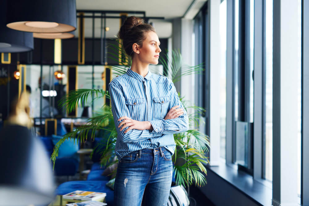 Une femme d'affaires en chemise en jean dans un bureau moderne, illustrant le profil d'un indépendant qui recherche la meilleure mutuelle pour les professions libérales.