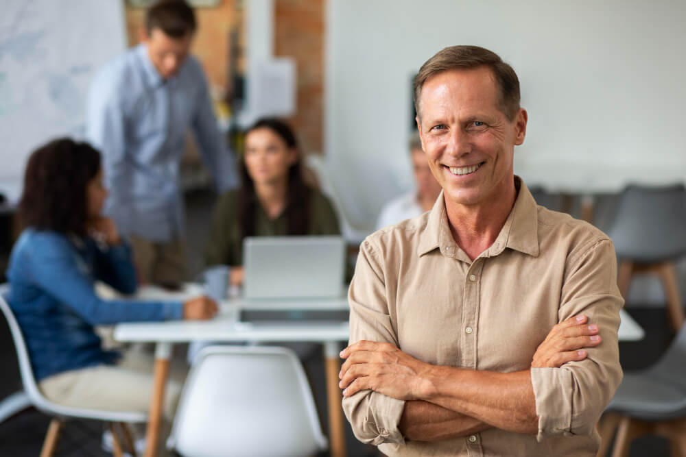 Un homme d'affaires souriant et confiant dans un bureau moderne, illustrant le succès et le rendement du contrat d'assurance-vie pour l'épargnant.