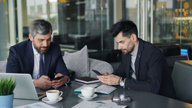 Deux professionnels étudient un comparatif en ligne pour trouver la meilleure assurance emprunteur depuis leur espace de travail.