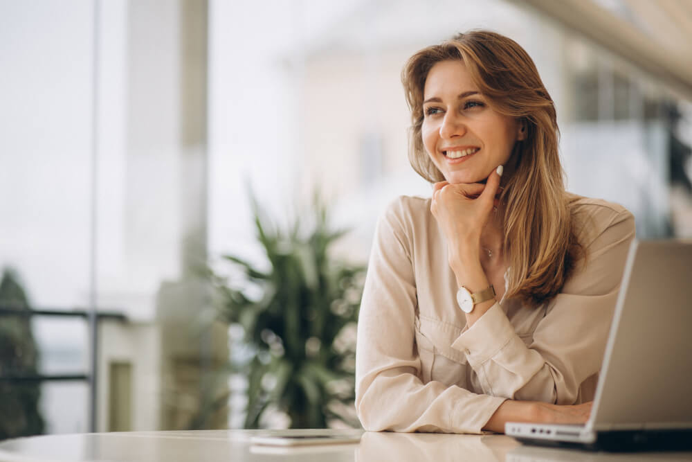 Une emprunteuse sereine devant son ordinateur se renseigne sur l'assurance emprunteur.