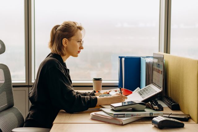 Une courtière concentrée travaillant à son bureau pour analyser les avantages juridiques d'une clause de remploi en assurance-vie.