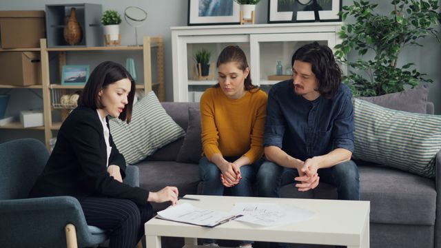 Un couple attentif écoutant une courtière présenter les spécificités de la clause de remploi en assurance-vie.