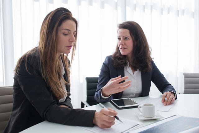 Deux femmes en entretien professionnel étudiant les démarches de délégation d'assurance emprunteur avec leur courtière.