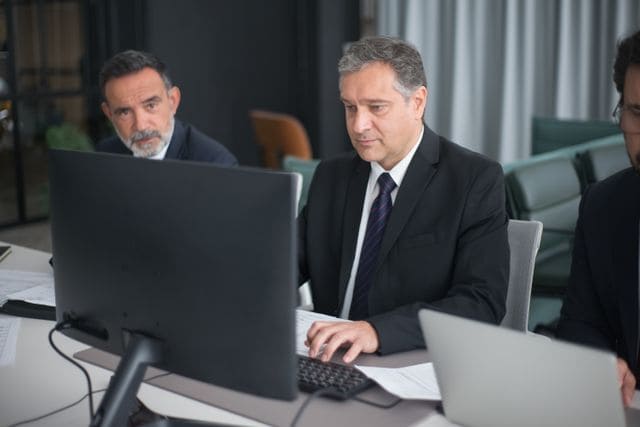 Conseillers analysant l'IFI (Impôt sur la Fortune Immobilière) sur écran d'ordinateur en bureau.