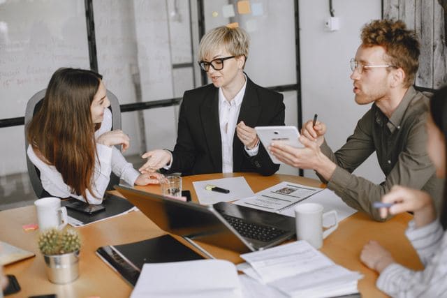 Une équipe de courtiers-experts en réunion de travail comparant les garanties d'une assurance emprunteur forfaitaire pour leurs clients.